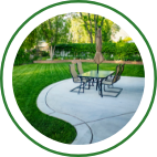 A large, landscaped backyard with green grass and a patio seating area. 